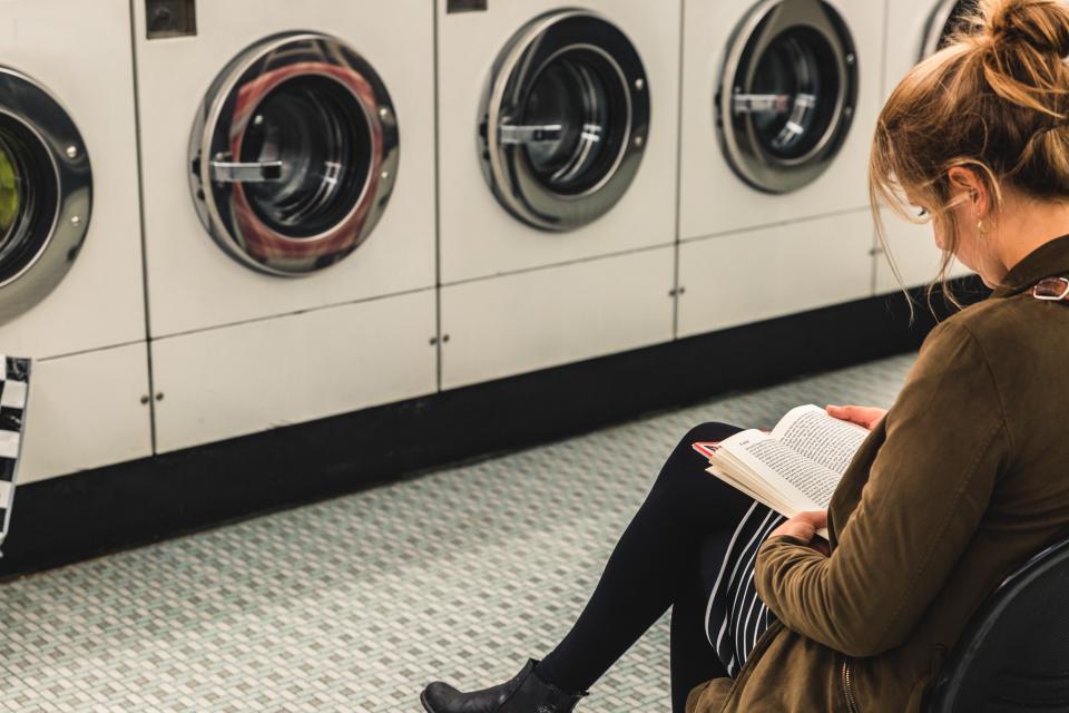een vrouw leest een boek in een wassalon.