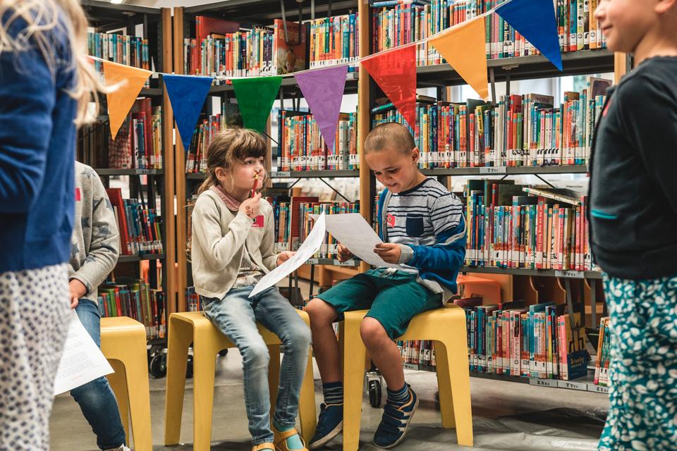 Kinderen nemen deel aan een boekenzoektocht in de bibliotheek