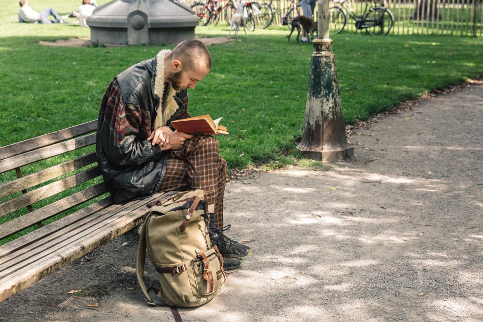 man leest boek op een bank in het park