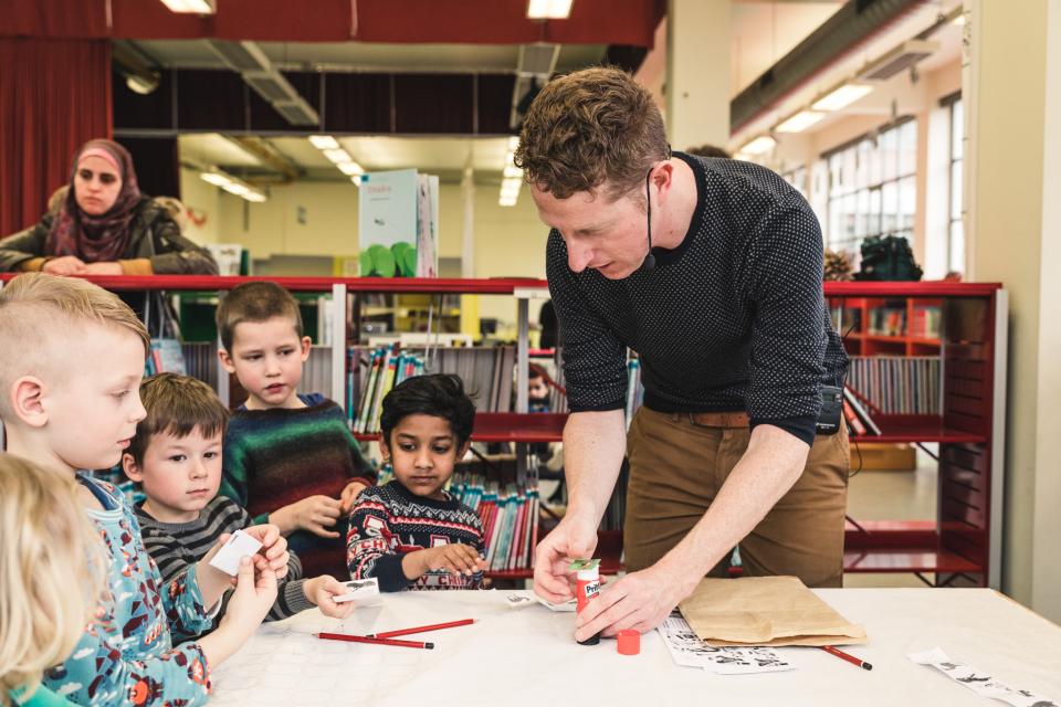 kinderen knutselen een eigen verhaal tijdens een workshop met een illustrator in de bibliotheek