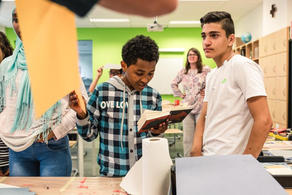 twee jongeren kijken in een boek tijdens een workshop in de klas met een jeugdauteur