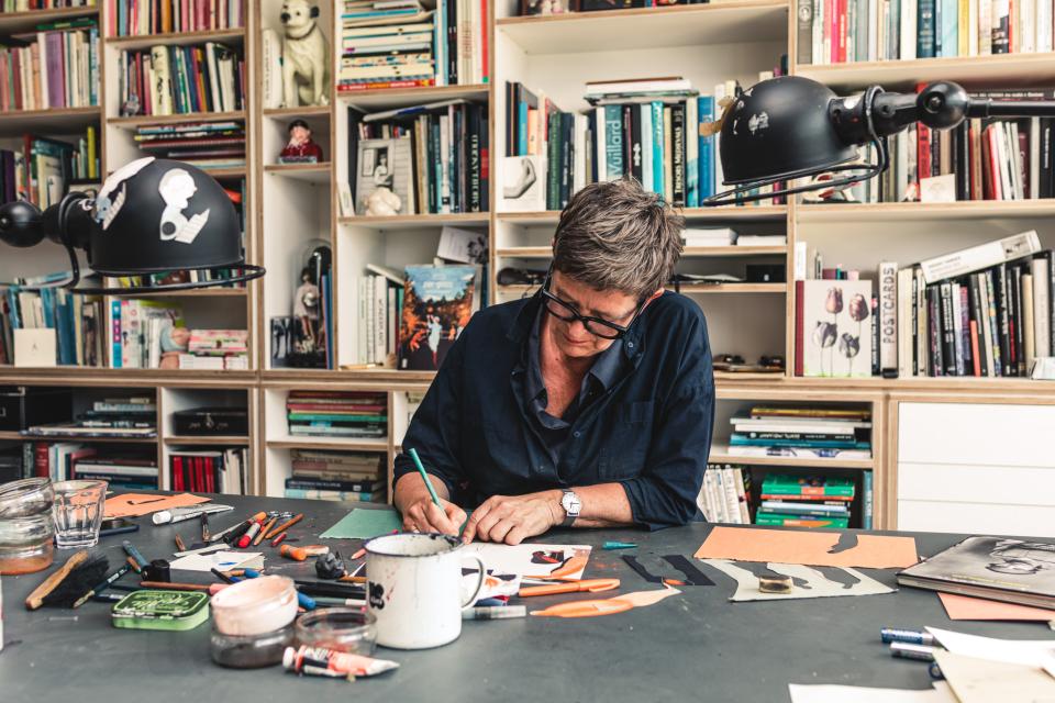 illustrator ingrid godon tekent op papier aan een bureau in haar atelier